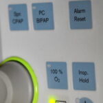 Bedienfeld eines Beatmungsgeräts mit Tasten für verschiedene Beatmungsmodi wie CPAP und BIPAP sowie Funktionen wie „100 % O2“ und „Alarm Reset“.