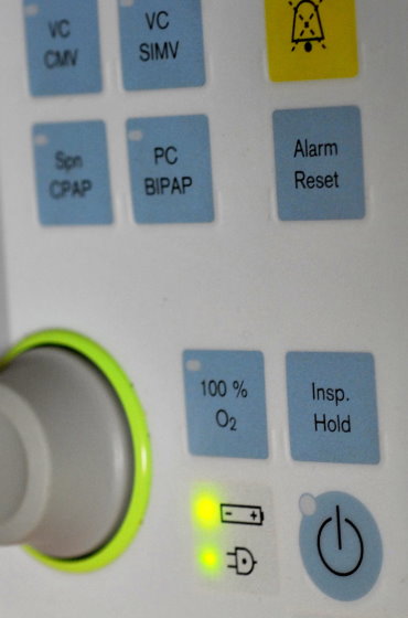 Bedienfeld eines Beatmungsgeräts mit Tasten für verschiedene Beatmungsmodi wie CPAP und BIPAP sowie Funktionen wie „100 % O2“ und „Alarm Reset“.