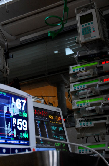 Intensivmedizinische Ausstattung: Mehrere Monitore zur Überwachung von Vitalparametern im Vordergrund und ein Turm mit Infusionsspritzenpumpen (Perfusoren) im Hintergrund.
