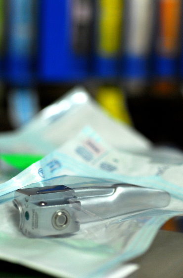 Ein steril verpackter Laryngoskop-Spatel aus Metall für die Intubation, bereitgelegt auf einer Arbeitsfläche im klinischen Bereich.