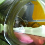 Blick durch eine geöffnete Klappe in das Innere eines Inkubators (Brutkasten) auf einer Neonatologie-Station. Zu sehen sind eine weiche Unterlage und ein weißes Tuch.
